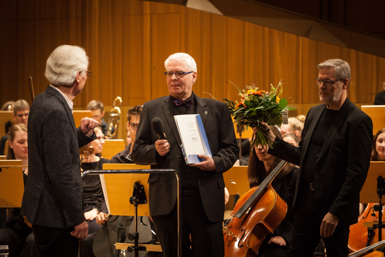 Wulf Hilbert, BDLO-Präsidiumsmitglied und Vorsitzender des BDLO-Nord, und Dr. Helge Amtenbrink, Vorsitzender der HOV, gratulieren Cord-Hinrich Flachsbarth (in der Mitte) mit Ehrennadel, Urkunde und Blumenstrauß – anhaltender Applaus im großen Saal der Radiophilharmonie Hannover